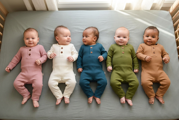 Vijf baby’s naast elkaar in ribgebreide boxpakjes in oudroze, ecru, petrolblauw, olijfgroen en caramel